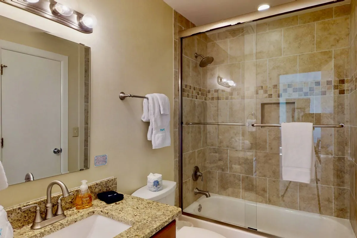 A modern, spa-inspired bathroom featuring a granite countertop, glass shower enclosure, and sleek fixtures. The calming elements invite guests to unwind and enjoy a refreshing shower or relaxing self-care routine, echoing the luxury of the en-suite bathrooms.